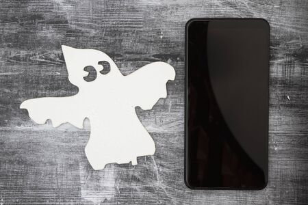 Ghosting someone online message with a white ghost and cell phone on weathered black grunge woodの写真素材