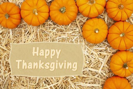 Happy Thanksgiving greeting with yellow straw hay and orange pumpkinsの写真素材