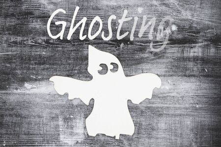 Ghosting someone message with a white ghost on weathered black grunge wood