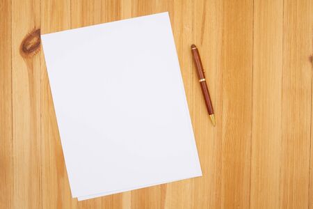 Pen and paper on pine wood desk with grain texture with copy space for your business or writing messageの写真素材