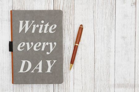 Write every day message on a leather book with pen on weathered whitewash wood の写真素材