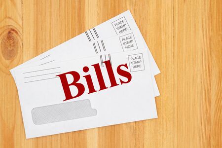 Pile of bills message on white business envelope on a wood deskの写真素材