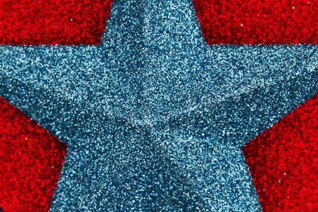 Closeup of a blue star on red glitter textured paper with a very shallow depth of fieldの写真素材