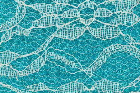 Delicate lace textured material on teal paper background with copy space for message or use as a texture の写真素材