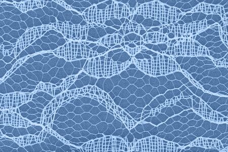 Delicate lace textured material on blue knit background with copy space for message or use as a...