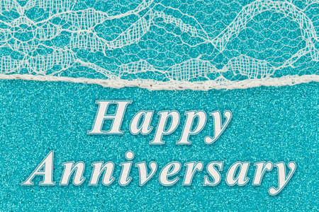 Happy Anniversary word message with delicate lace textured material on teal paperの写真素材