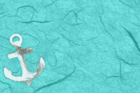 Whitewash wood anchor on teal textured cardstock paper background with copy space for beach or summer messageの写真素材