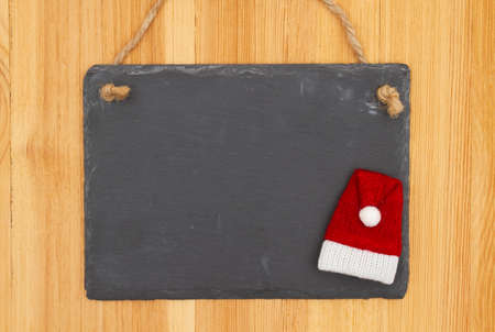 Christmas blank hanging chalkboard sign on wood Santa hat with copy space for your xmas or holiday messageの写真素材