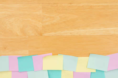Sticky note background with multi-color notes on a wood desk wood with copy space for your office or reminder messageの写真素材
