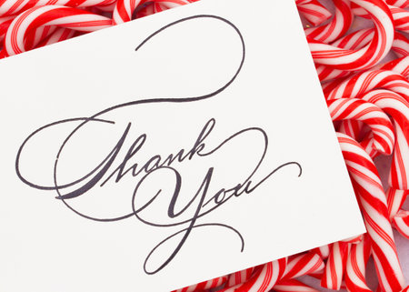 Christmas Thank You greeting card on a pile of candy canes on a pile of red and white candy canesの写真素材