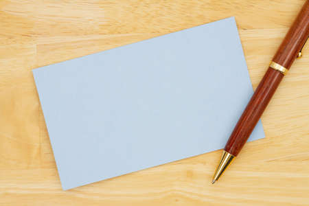 Blank blue paper index card with pen on wood desk with copy space for your messageの写真素材