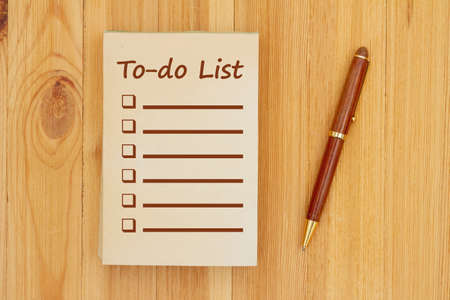 To-do list on an old paper notepad with pen on wood deskの写真素材