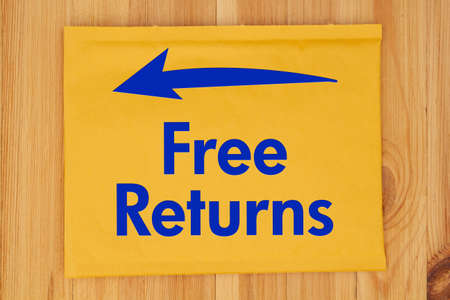 Free Returns message on yellow bubble mailing envelope with an arrow on a wood desk