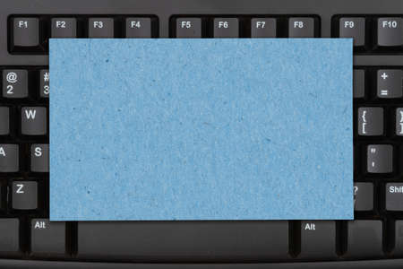 Blank blue card on a black keyboard with copy space for your tech messageの写真素材