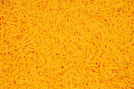 Shredded cheddar cheese in pile background with copy space for your snack message