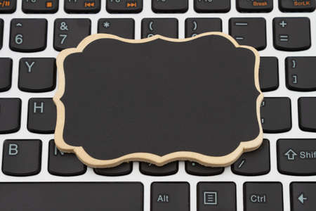 Blank chalkboard on a black and silver keyboard with copy space for your tech or online message