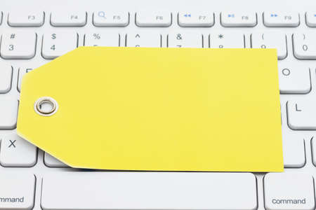 Blank yellow gift tag on gray keyboard with copy space for your online sales messageの写真素材