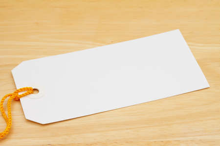 Blank gift tag with yellow ribbon on wood desk with copy space for your gifting messageの写真素材