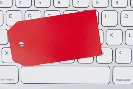 Blank red gift tag on gray keyboard with copy space for your tech of business message