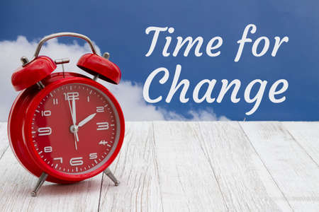 Time for change message with a red alarm clock on weathered wood with sky
