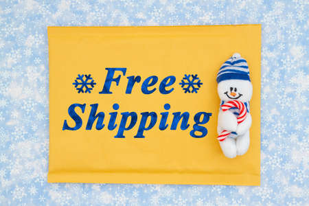 Free Shipping message on yellow padded envelope with snowman with candy cane on blue with snowflakesの写真素材