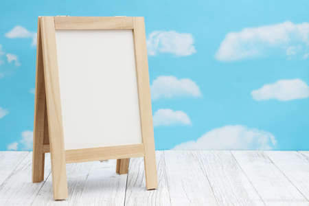 Blank standing whiteboard on weathered wood with clear sky with copy space for your message
