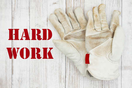 Hard Work message with dirt covered leather work gloves on weathered woodの写真素材