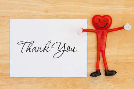 Thank you greeting card on a desk with a happy smiling heart for thanking your customers for their businessの写真素材