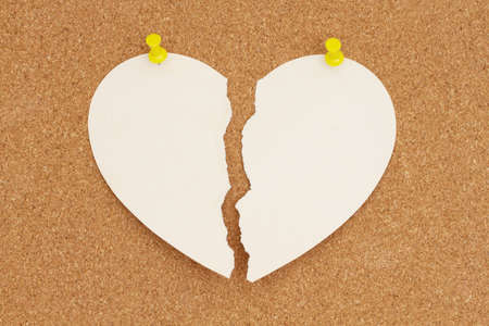 Ripped torn apart paper heart on a bulletin board for your divorce or heartbroken messageの写真素材