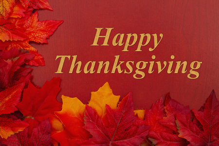 Happy Thanksgiving message with orange fall leaves on red wood