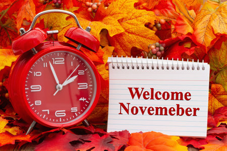 Welcome November message on a notepad with an alarm clock and fall leavesの写真素材