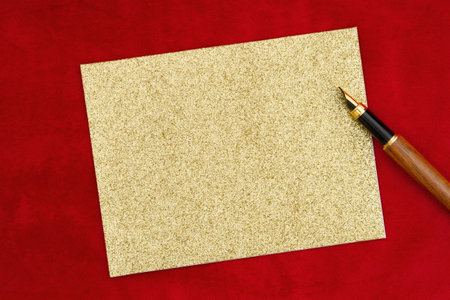 Blank greeting card on red plush material with a fountain pen for your holiday messageの写真素材