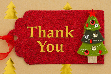 Thank You message on red holiday gift tag with a Christmas tree on goldの写真素材