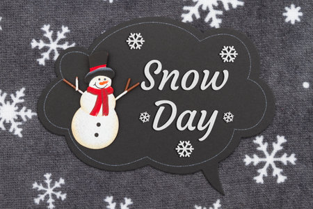 Snow day message on a talk bubble chalk sign with a snowman on snowflake fabric