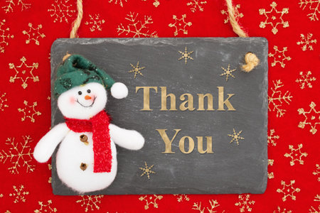 Thank you message on a chalkboard sign with a snowman on snowflakesの写真素材