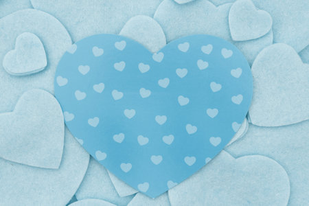 Lots of blue felt hearts with paper heart love background for your romance or dating messageの写真素材