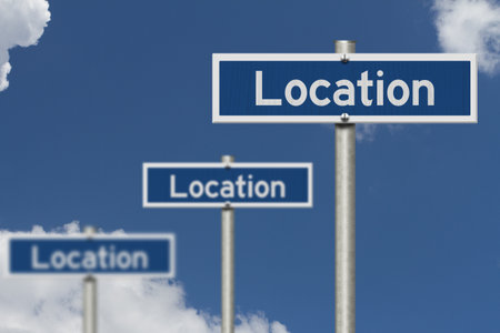 Location on three blue street signs for real estate with skyの写真素材