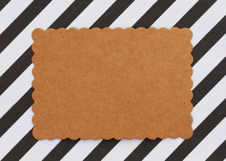 Blank paper textured brown gift tag on black and white stripesの写真素材