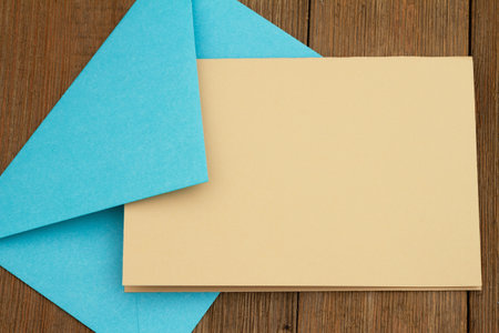 Blank greeting card with blue envelope on weathered woodの写真素材
