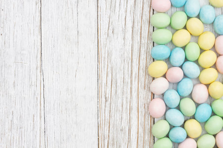 Easter egg background of pastel color candy on weathered wood for your holiday message