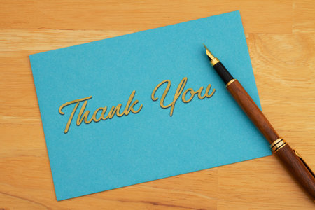 Thank you greeting blue card and pen on wood deskの写真素材
