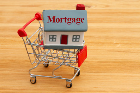 Mortgage payment when buying a home with a red shopping cart with a house on a wood deskの写真素材