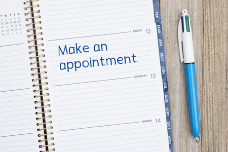 Make an appointment on day planner with pen on weathered wood deskの写真素材
