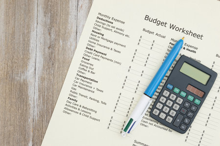 Monthly personal budget with a pen and calculator on weathered wood desk