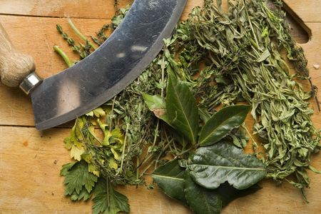 Various herbs with a mincing knife on a chopping boardの写真素材