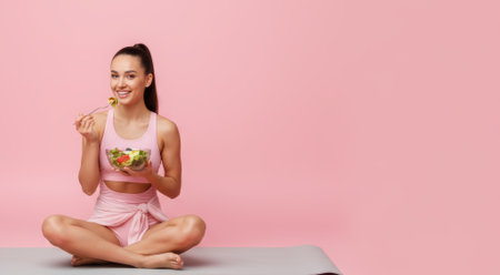 Fitness, girl eating salad on exercise mat, healthy food, proper nutrition, healthy lunch, health care, exercise, yoga. High qualityの素材