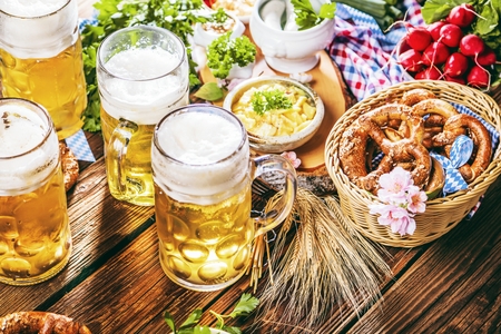 Oktoberfest beer, pretzels and various Bavarian specialties on wooden backgroundの写真素材
