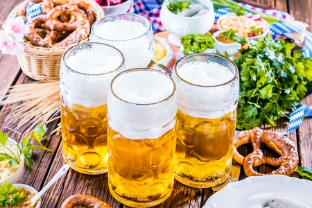 Oktoberfest beer, pretzels and various Bavarian specialties on wooden backgroundの写真素材