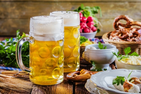 Oktoberfest beer, pretzels and various Bavarian specialties on wooden backgroundの写真素材