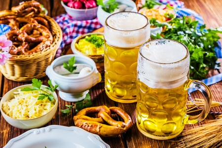 Oktoberfest beer, pretzels and various Bavarian specialties on wooden backgroundの写真素材